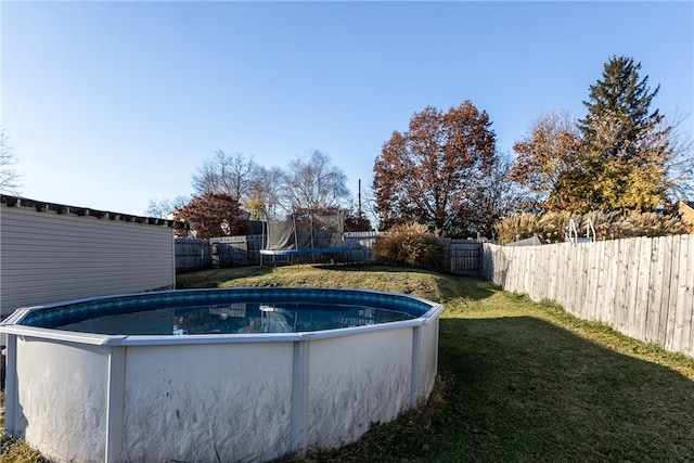 view of swimming pool featuring a trampoline and a lawn