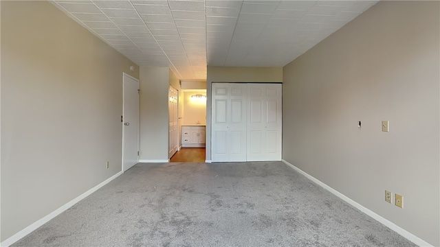 unfurnished bedroom featuring ensuite bath, a closet, and carpet flooring