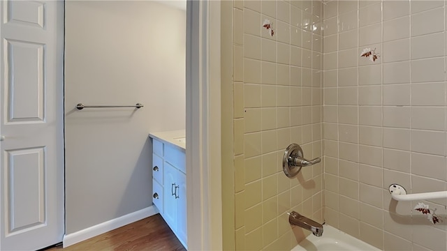 bathroom with wood-type flooring, vanity, and tiled shower / bath