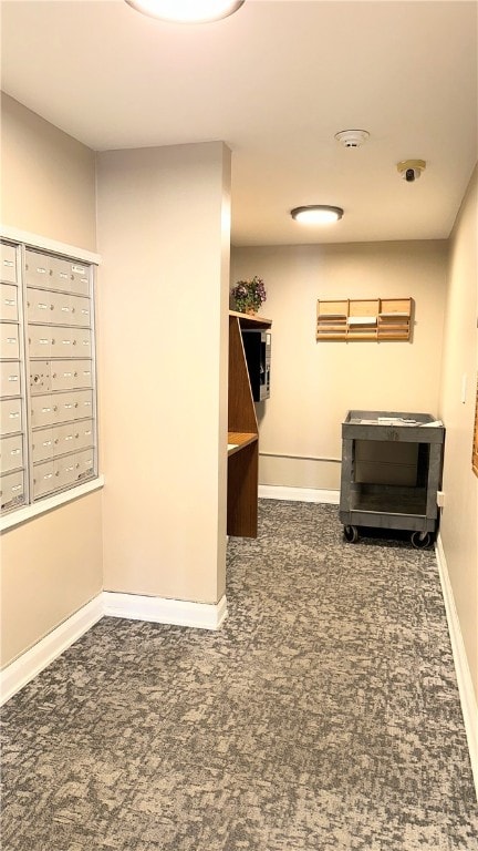 interior space featuring a mail area and dark carpet