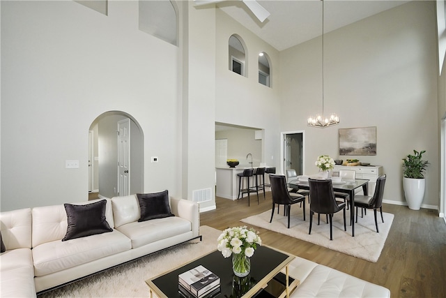 living room featuring high vaulted ceiling, a chandelier, and wood-type flooring