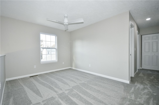 empty room featuring ceiling fan and dark colored carpet