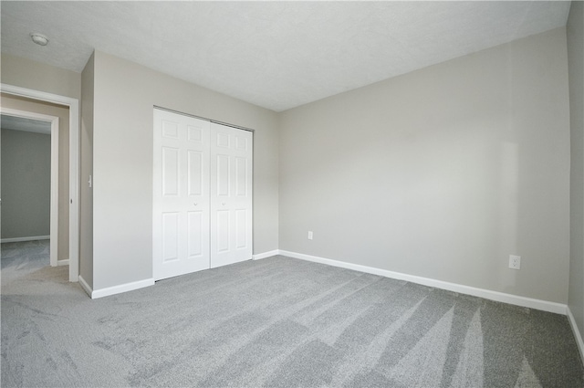 unfurnished bedroom featuring carpet floors, a textured ceiling, and a closet