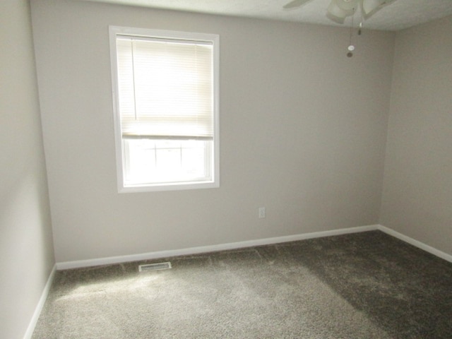 carpeted spare room featuring a healthy amount of sunlight and ceiling fan