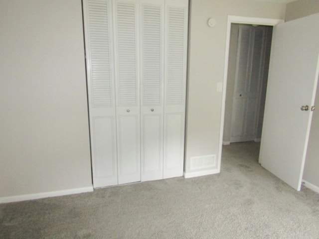 unfurnished bedroom featuring light carpet and a closet