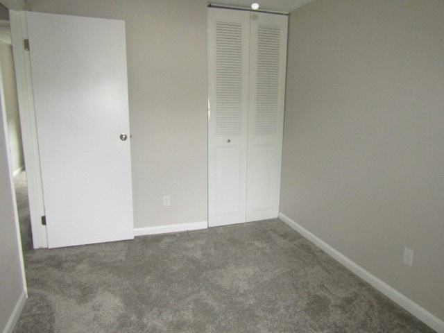 unfurnished bedroom featuring dark carpet and a closet