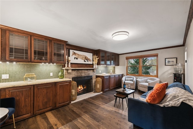 living room with dark wood-type flooring, a fireplace, and ornamental molding