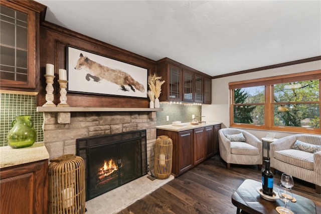 living room with a stone fireplace, dark hardwood / wood-style flooring, and ornamental molding