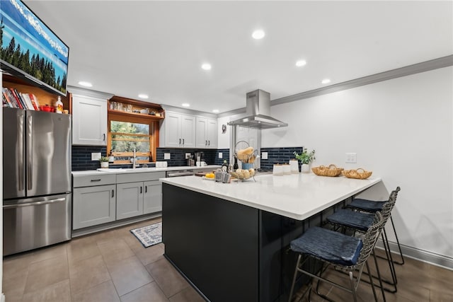 kitchen featuring decorative backsplash, kitchen peninsula, a kitchen breakfast bar, exhaust hood, and stainless steel refrigerator