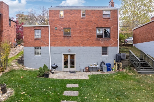 back of property with french doors, central air condition unit, and a lawn