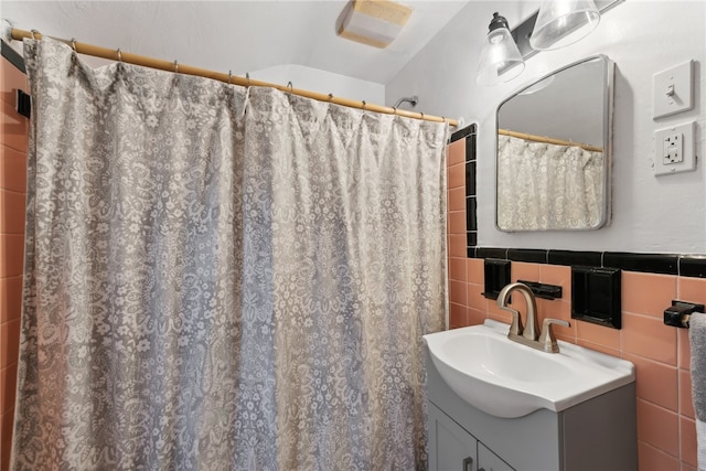 bathroom featuring a shower with shower curtain, vanity, and tile walls