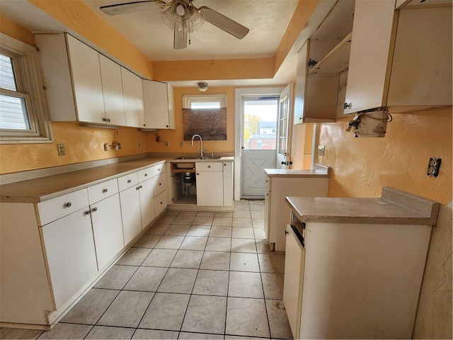 kitchen featuring sink, light tile patterned floors, ceiling fan, and white cabinets