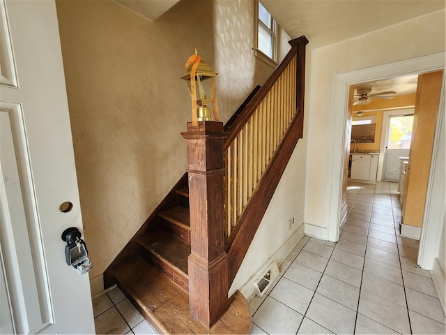 staircase with ceiling fan, tile patterned floors, and sink