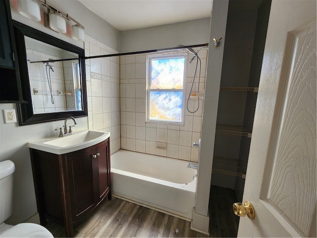 full bathroom featuring hardwood / wood-style flooring, vanity, toilet, and tiled shower / bath combo