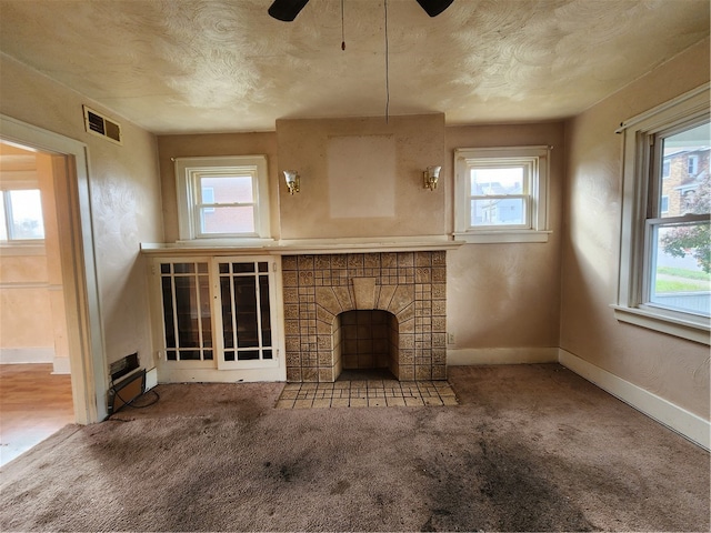 unfurnished living room with carpet flooring, a healthy amount of sunlight, and a fireplace