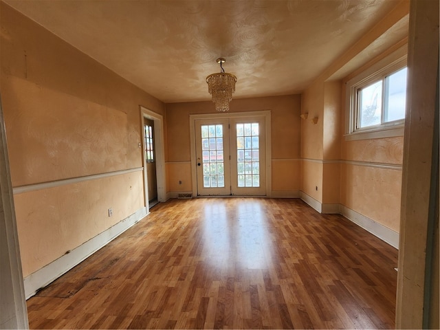 spare room with hardwood / wood-style flooring, a wealth of natural light, and a notable chandelier