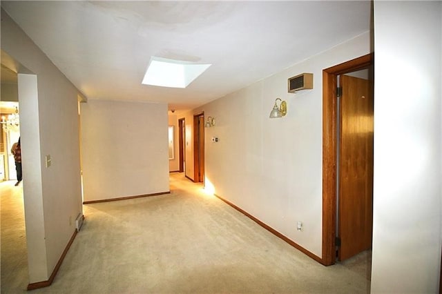 hall featuring a skylight, an inviting chandelier, and light colored carpet