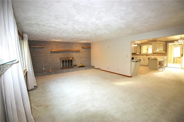 unfurnished living room featuring a brick fireplace and a chandelier