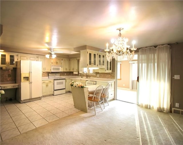 kitchen with white appliances, sink, light carpet, and hanging light fixtures