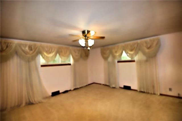 carpeted empty room with ceiling fan and plenty of natural light