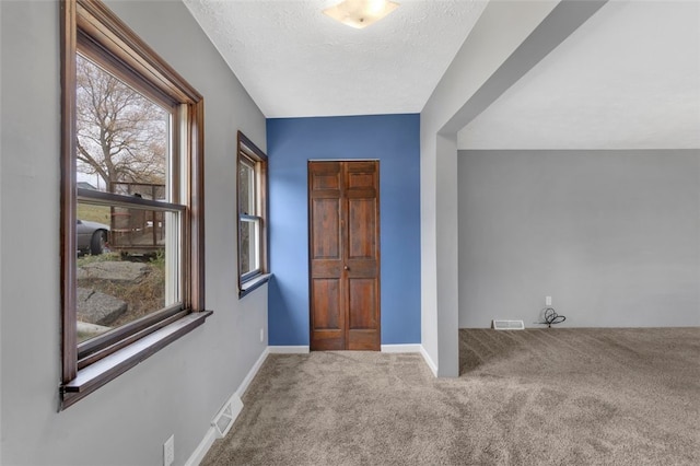 foyer entrance featuring carpet flooring and a textured ceiling