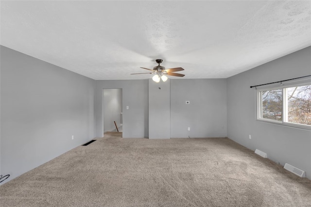 empty room featuring a textured ceiling, carpet floors, and ceiling fan