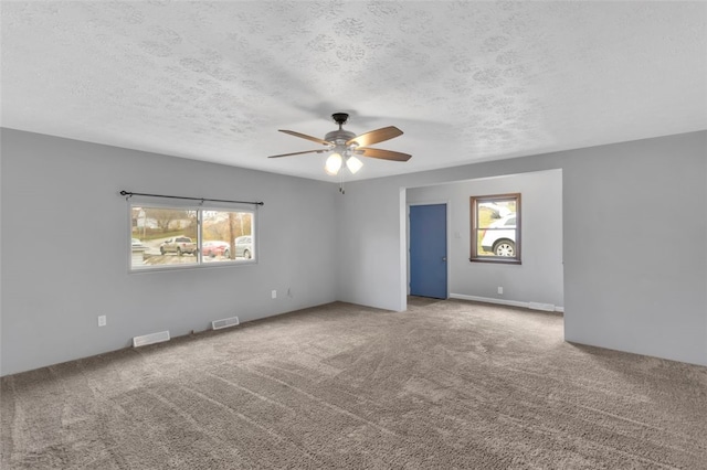 carpeted spare room with a textured ceiling and ceiling fan