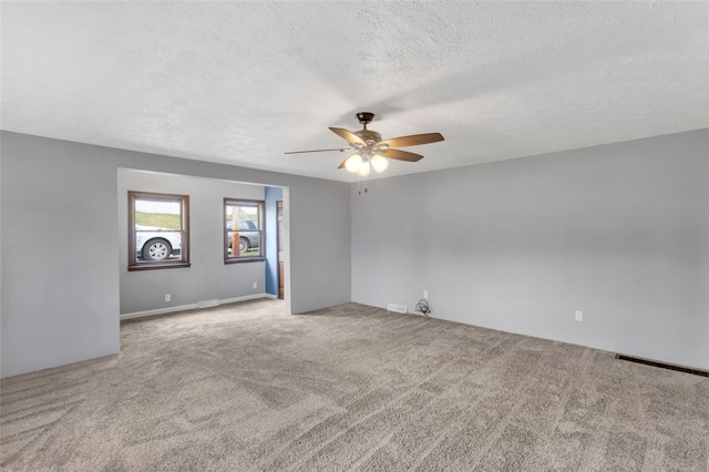 spare room featuring light colored carpet, a textured ceiling, and ceiling fan