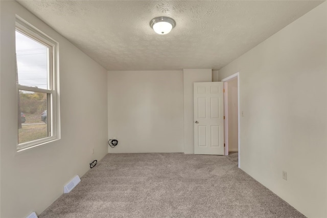 laundry area featuring a textured ceiling and light carpet