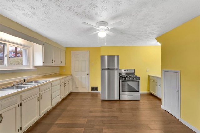 kitchen featuring white cabinetry, a textured ceiling, dark hardwood / wood-style floors, and stainless steel appliances