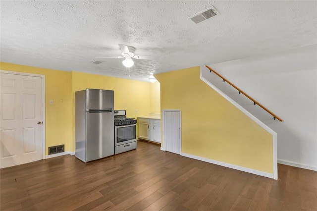 kitchen featuring a textured ceiling, stainless steel appliances, white cabinetry, and dark hardwood / wood-style floors