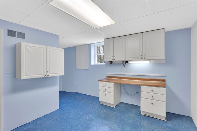 unfurnished office featuring a drop ceiling and built in desk