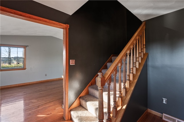 staircase with wood-type flooring and vaulted ceiling