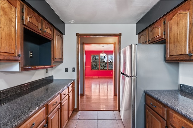 kitchen featuring pendant lighting, light hardwood / wood-style floors, and stainless steel refrigerator