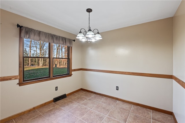 tiled empty room featuring an inviting chandelier