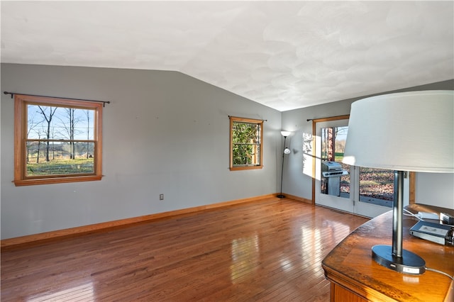 unfurnished living room featuring wood-type flooring and lofted ceiling