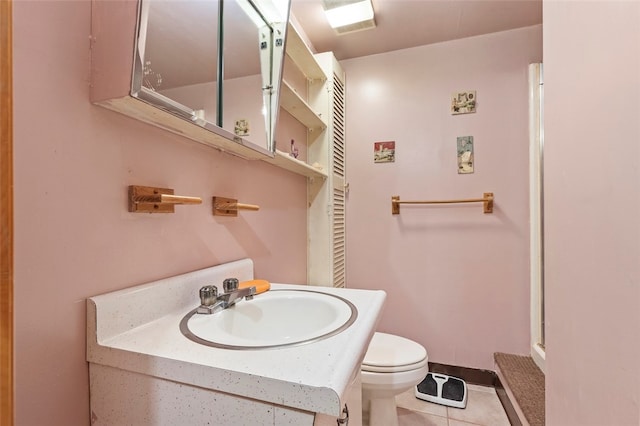 bathroom with toilet, vanity, and tile patterned flooring