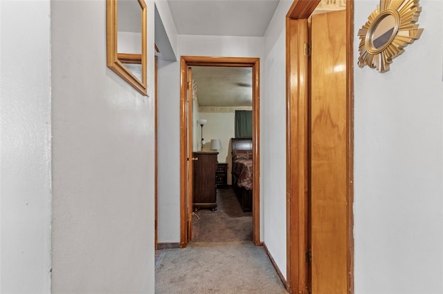 hallway featuring light carpet and baseboards