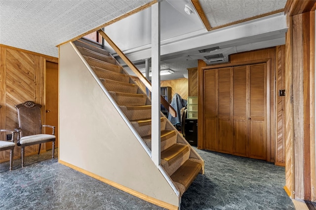 stairway featuring carpet and wooden walls