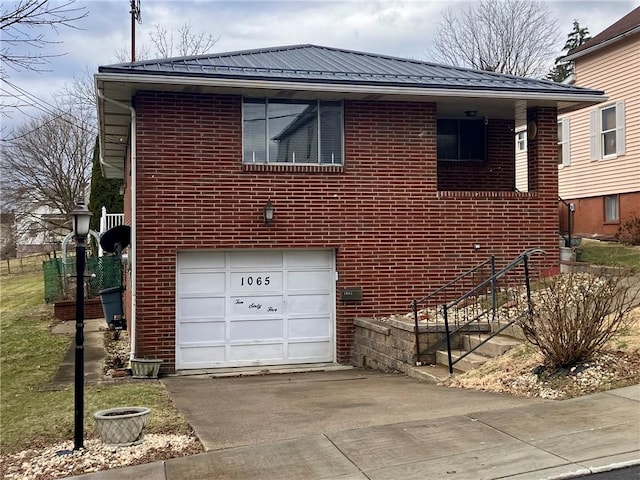 view of side of home with driveway, an attached garage, metal roof, and brick siding