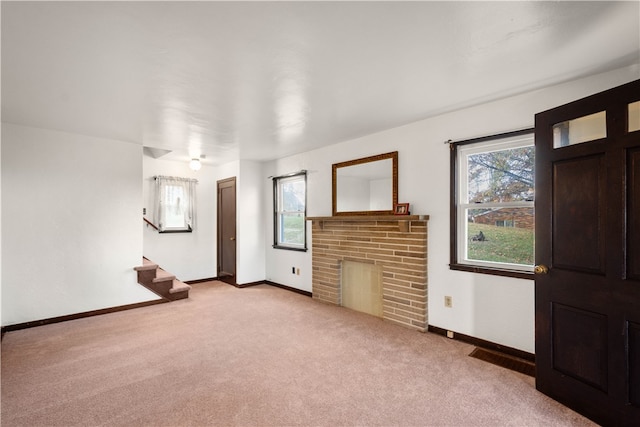 unfurnished living room with light colored carpet and a brick fireplace