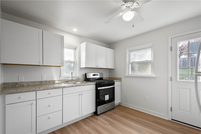 kitchen featuring white cabinets, a wealth of natural light, light hardwood / wood-style floors, and stainless steel range with gas cooktop