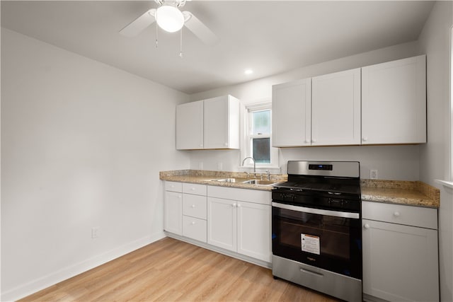 kitchen featuring white cabinetry, sink, ceiling fan, gas range, and light wood-type flooring