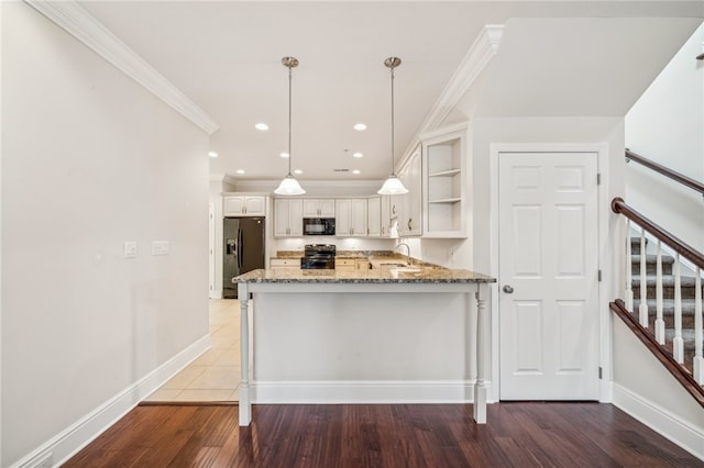 kitchen with black appliances, dark hardwood / wood-style flooring, kitchen peninsula, and sink