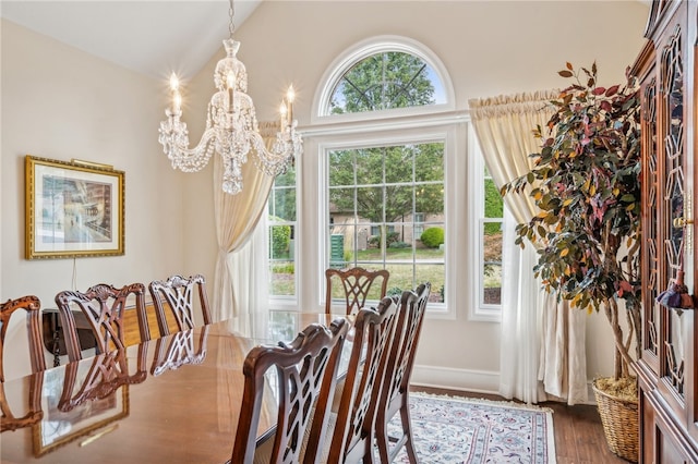 dining area featuring dark wood-type flooring, lofted ceiling, and a notable chandelier