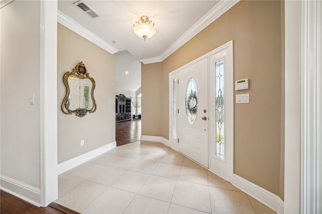 foyer with plenty of natural light, light tile patterned floors, and crown molding