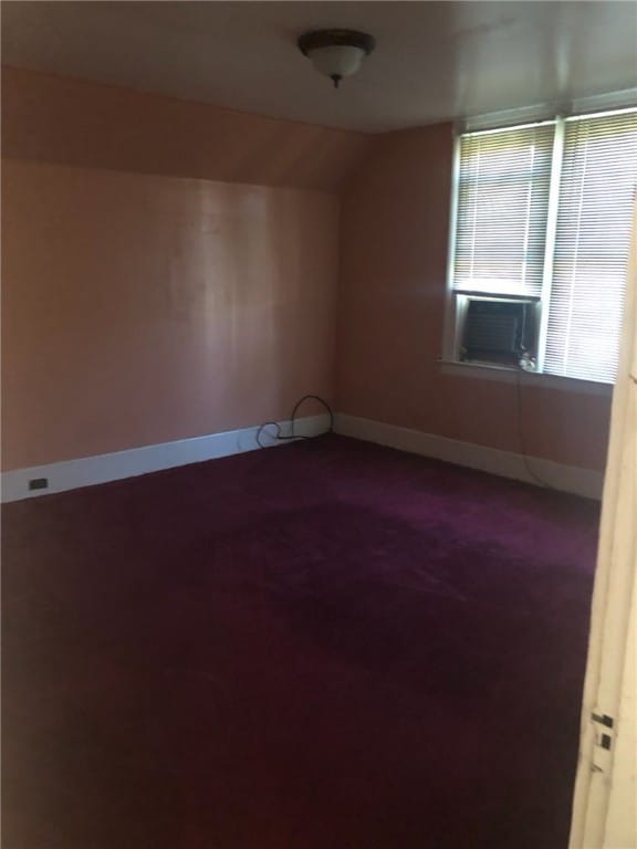 carpeted empty room with lofted ceiling and cooling unit