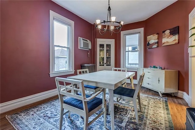 dining space featuring hardwood / wood-style flooring, an AC wall unit, and a notable chandelier