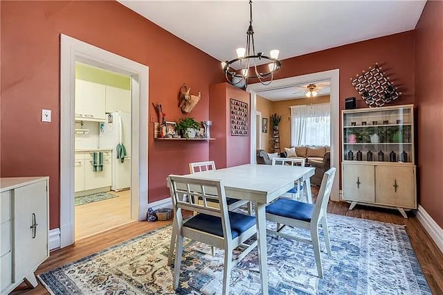 dining area with ceiling fan with notable chandelier and wood-type flooring