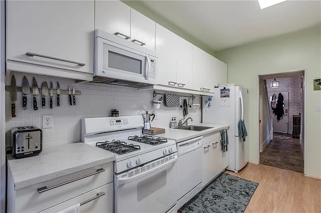 kitchen with decorative backsplash, sink, white cabinetry, light hardwood / wood-style flooring, and white appliances